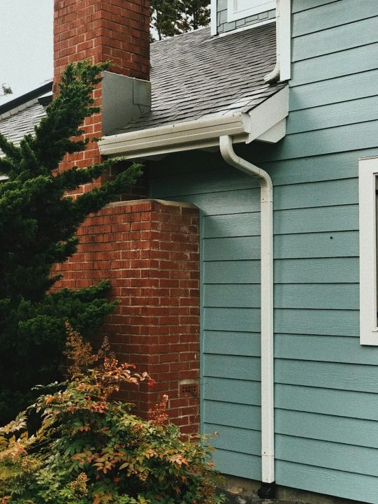 A white gutter pipe behind a house 